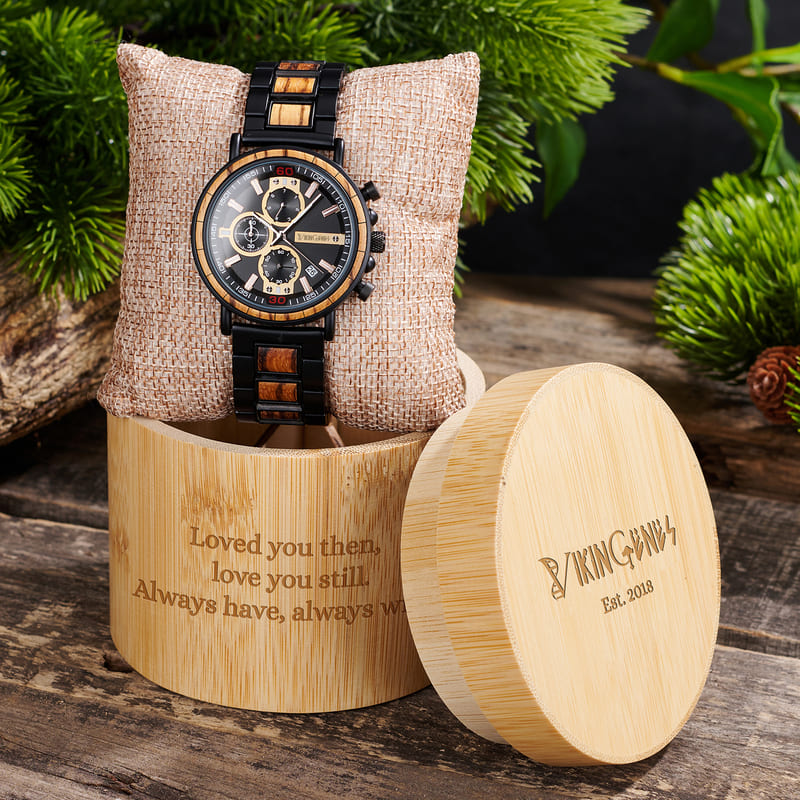 Wooden watch with engraved message and brand name on a wooden stand.