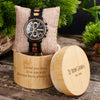 Wooden watch with engraved message and brand name on a wooden stand.