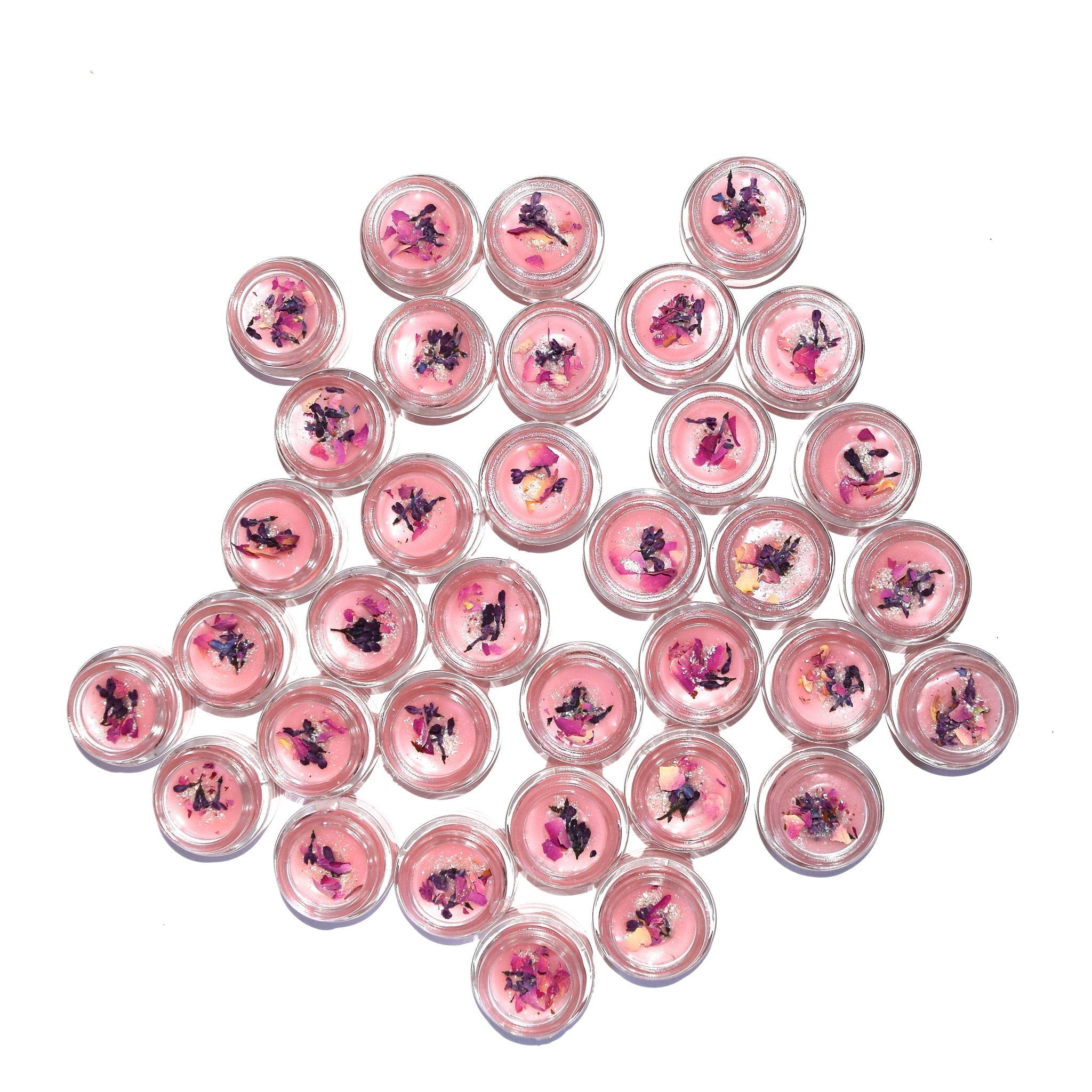 Multiple small round containers with pink contents on a white background