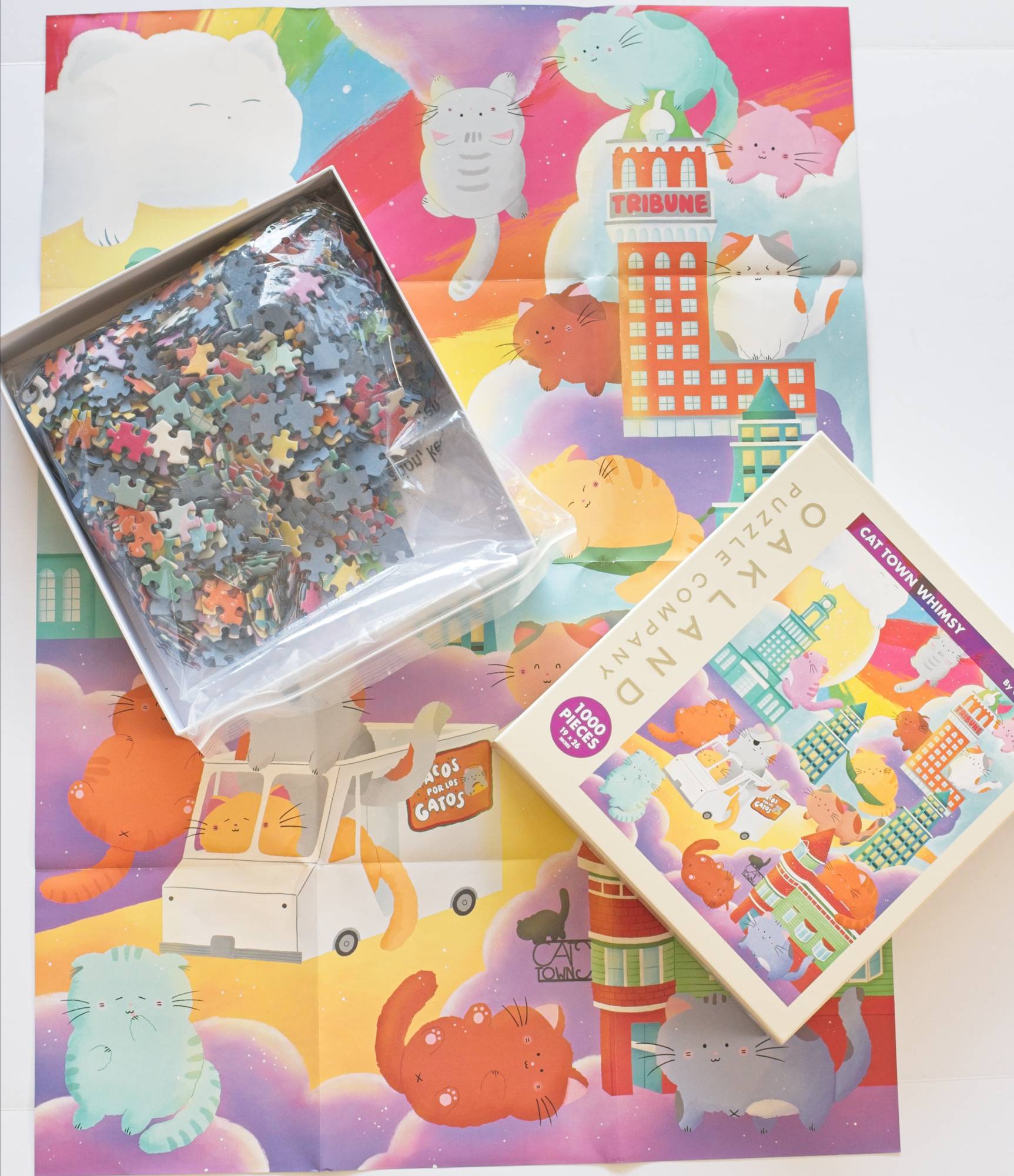Completed Cat Town Whimsy jigsaw puzzle showing cats frolicking among miniature Oakland buildings including Tribune Tower and City Hall