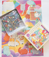 Completed Cat Town Whimsy jigsaw puzzle showing cats frolicking among miniature Oakland buildings including Tribune Tower and City Hall