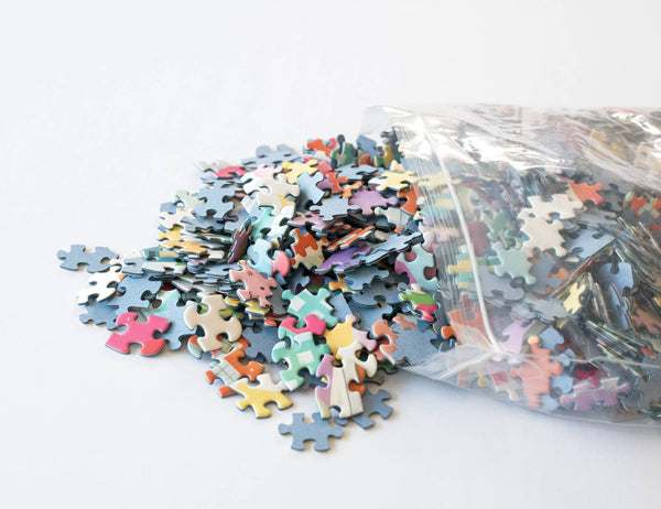 Colorful puzzle pieces spilling out of a clear plastic bag on a white background