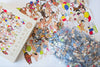 Close-up of Birthday Suits puzzle pieces showing ribbon-cut design, matte finish, and low-dust surface