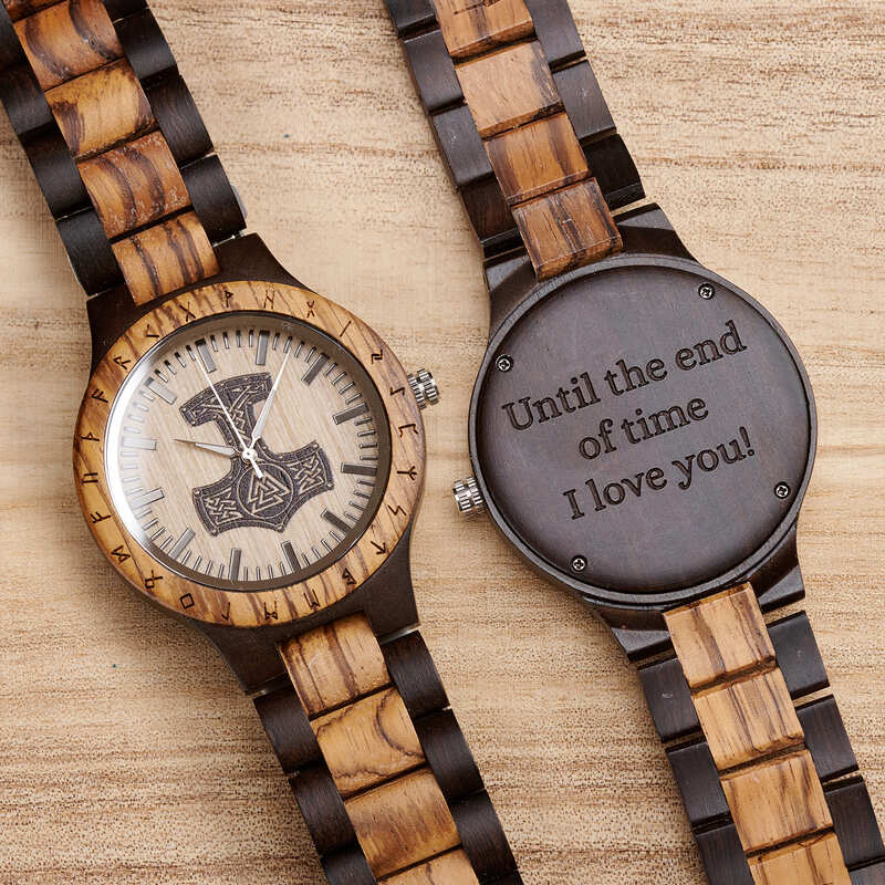 Two wooden watches with engraved designs on a wooden surface