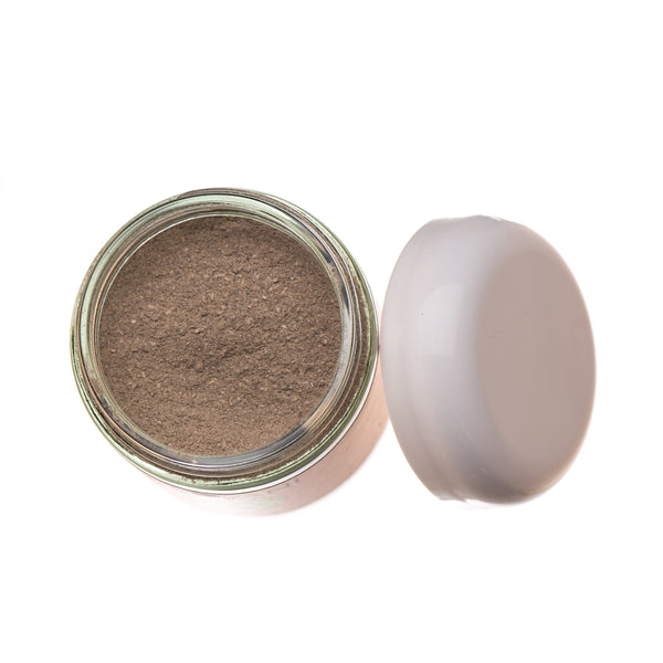 Open jar of brown powder with a white lid on a white background