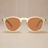 Sunglasses with gold frame and brown lenses on a beige background