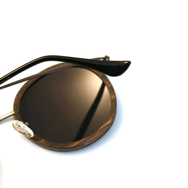 Sunglasses with gold frame and dark lenses on a white background