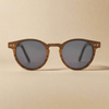 Wooden-framed sunglasses with dark lenses on a beige background
