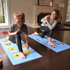 Two children on yoga mats with emoji designs in a home setting