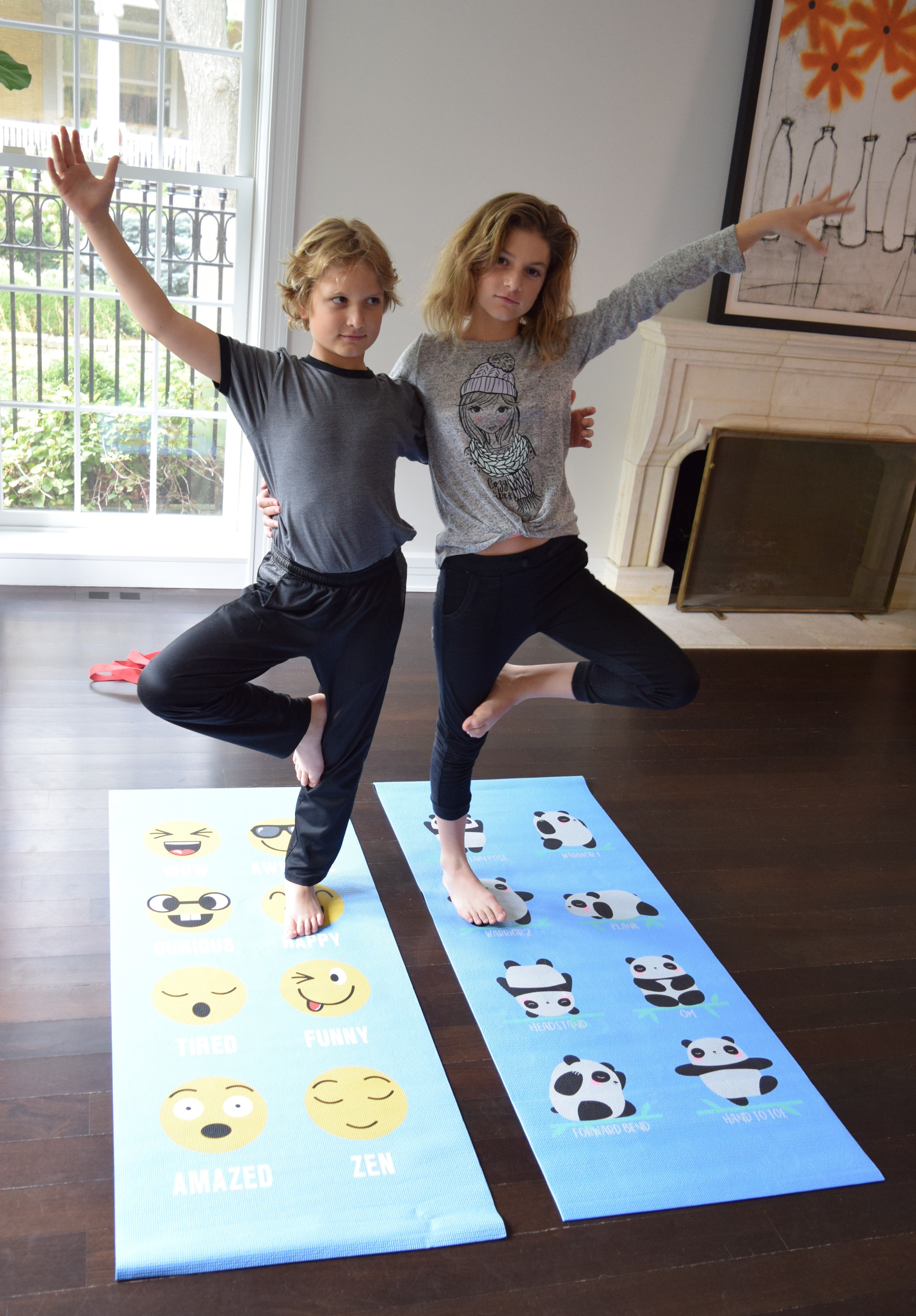 Two people practicing yoga on mats with emoji and panda designs in a home setting.