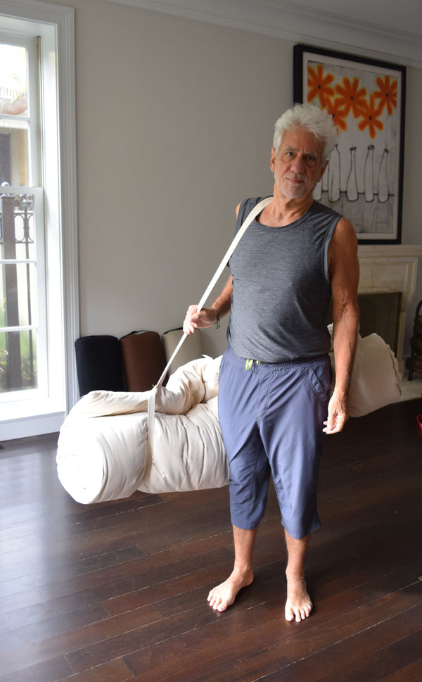 Man holding a broom in a living room with a couch and window in the background