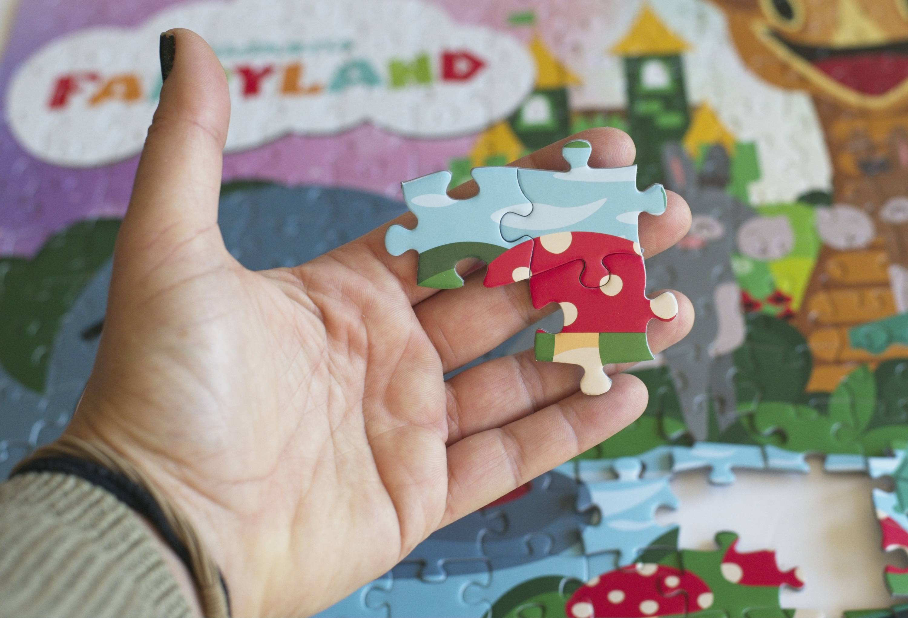 Close-up detail of the Children's Fairyland puzzle pieces showing ribbon-cut interlocking design and vibrant artwork by Greg Berger