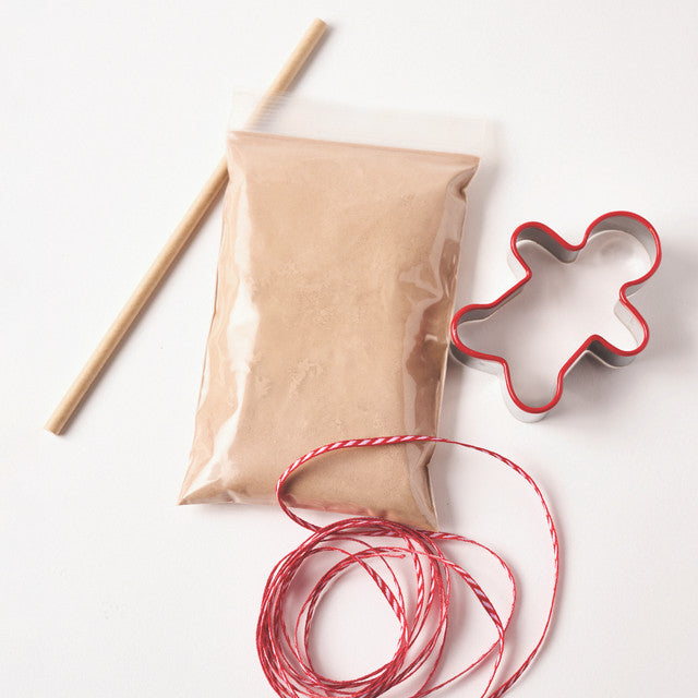 Kraft paper bag with a gingerbread man cookie cutter and red string on a white background
