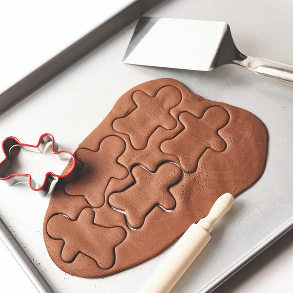 Chocolate cookie dough with gingerbread man shapes on a baking tray.