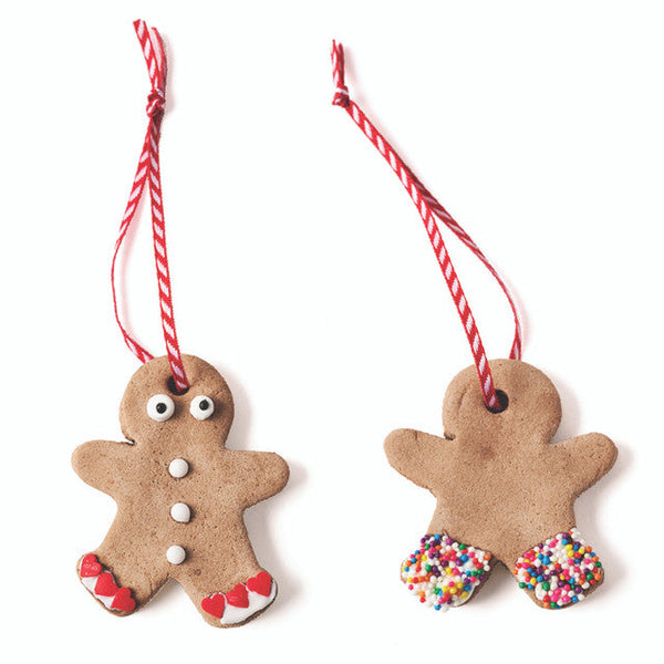 Two gingerbread man ornaments with red and white strings on a white background