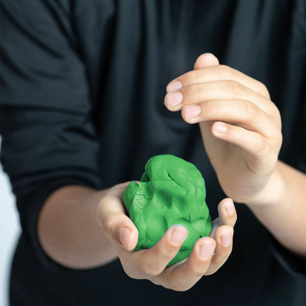 Person holding a green brain-shaped object against a black background