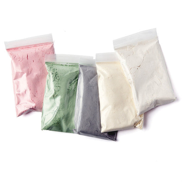 Four bags of different colored powders on a white background