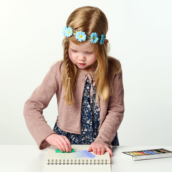 Young girl with a flower headband playing with colorful toys on a white background