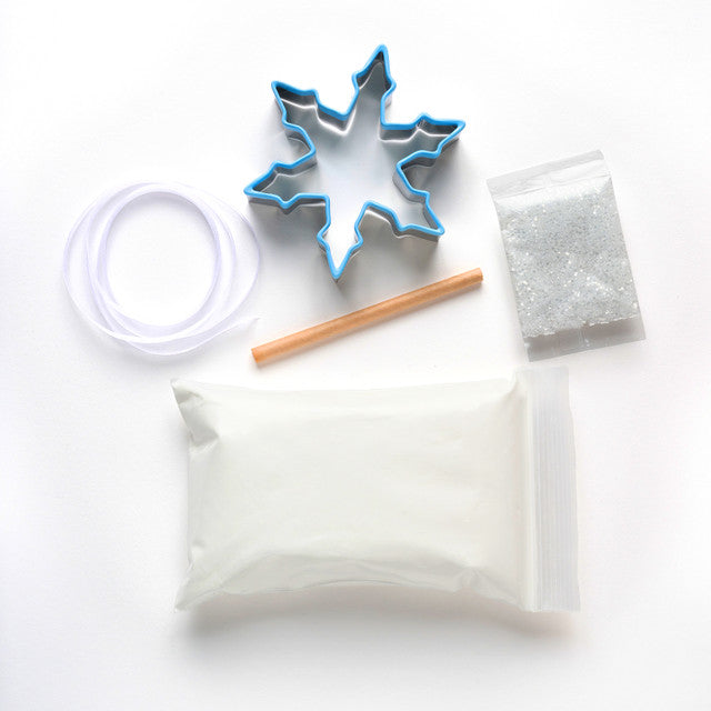 Cookie cutter, wooden stick, and small containers on a white background