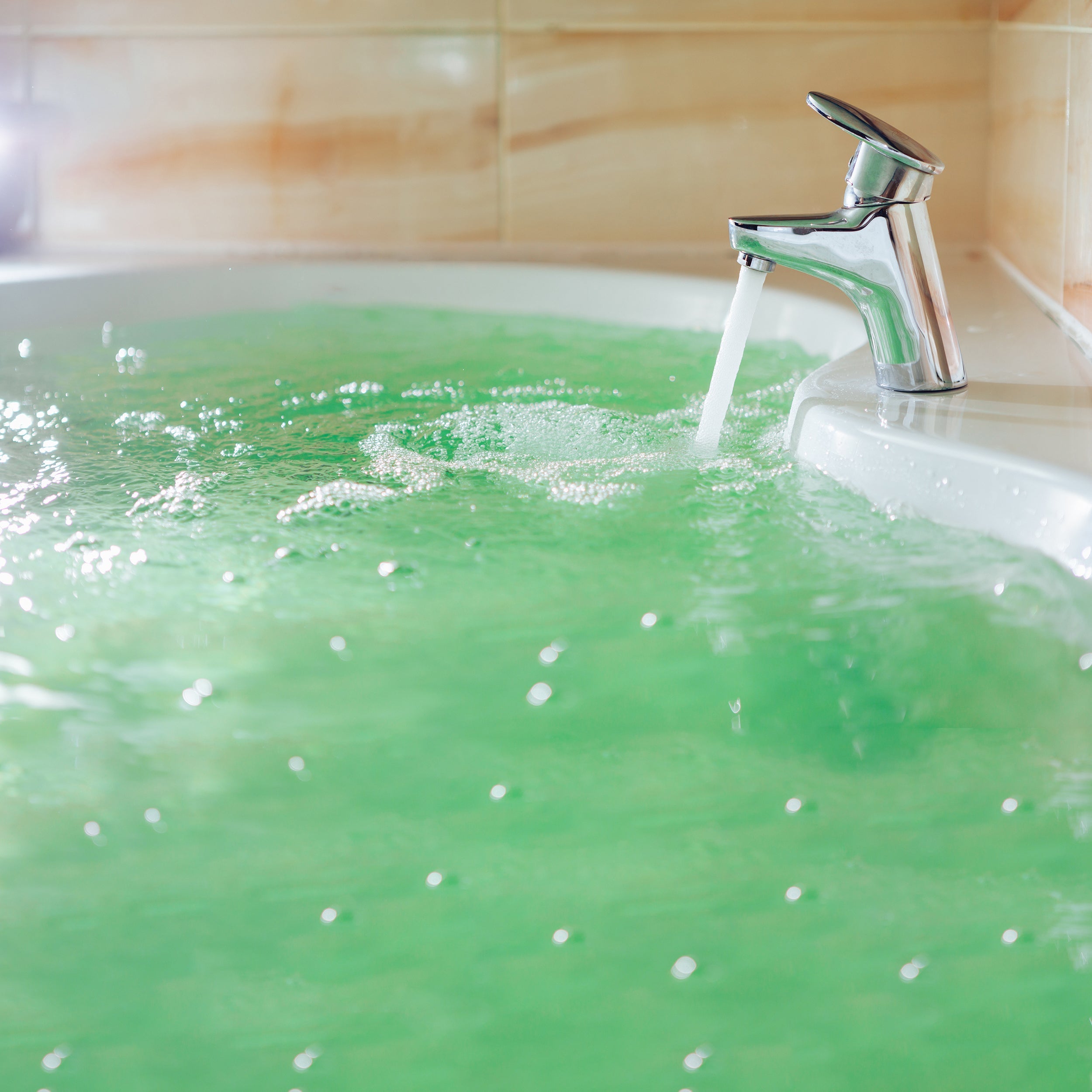 Green bathtub with a running faucet in a bathroom setting