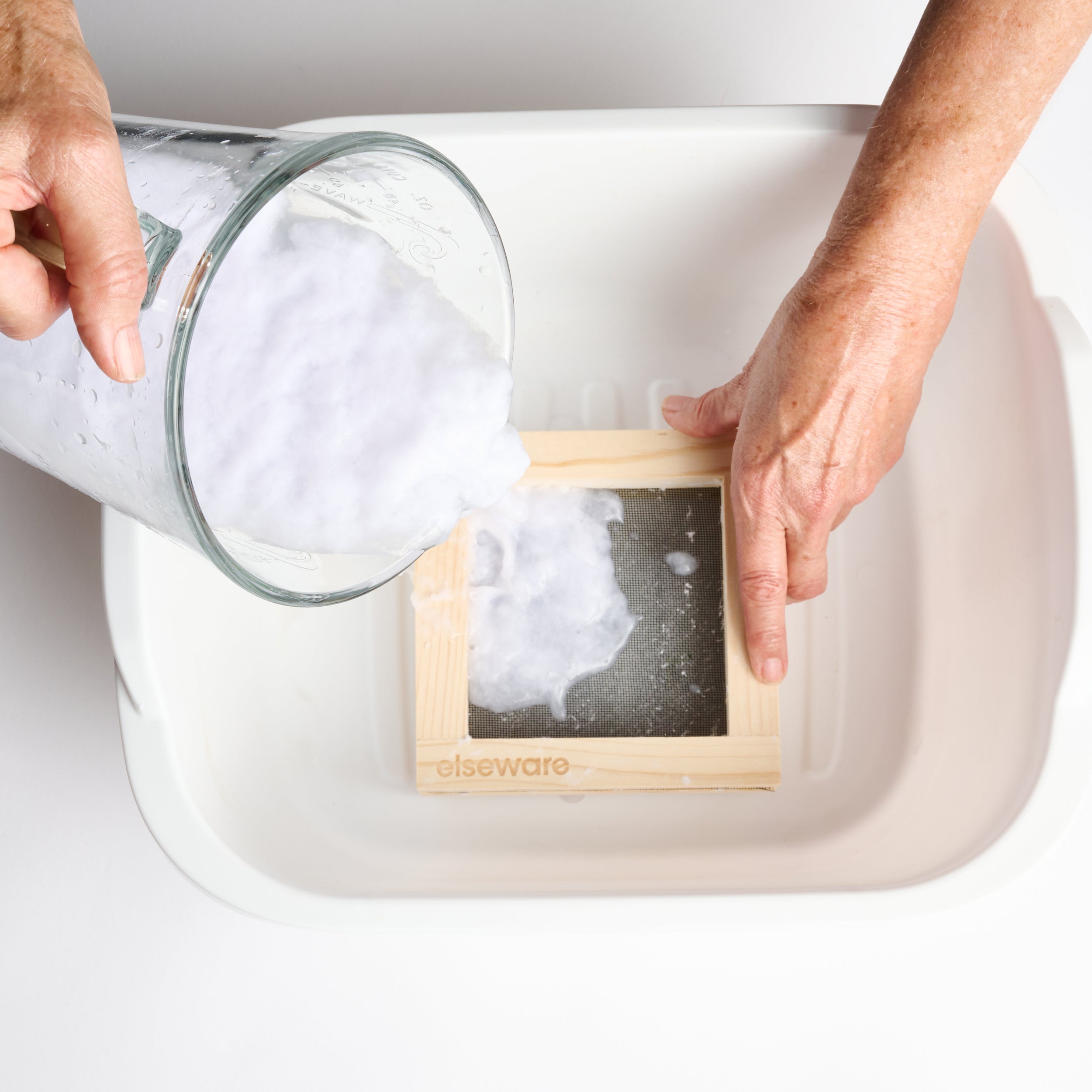 Person washing a wooden block with soapy water in a sink.