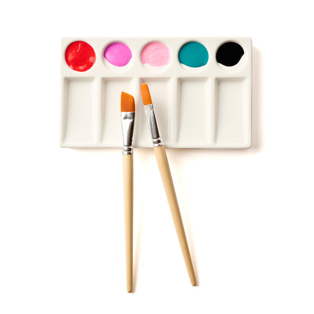 Paint palette with colorful paint samples and two brushes on a white background