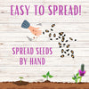 Illustration of seeds being spread by hand with text 'Easy to Spread! Spread Seeds by Hand' on a wooden background.