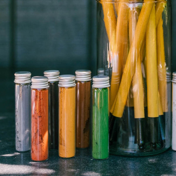 Set of colored tubes with a container of yellow straws on a dark surface