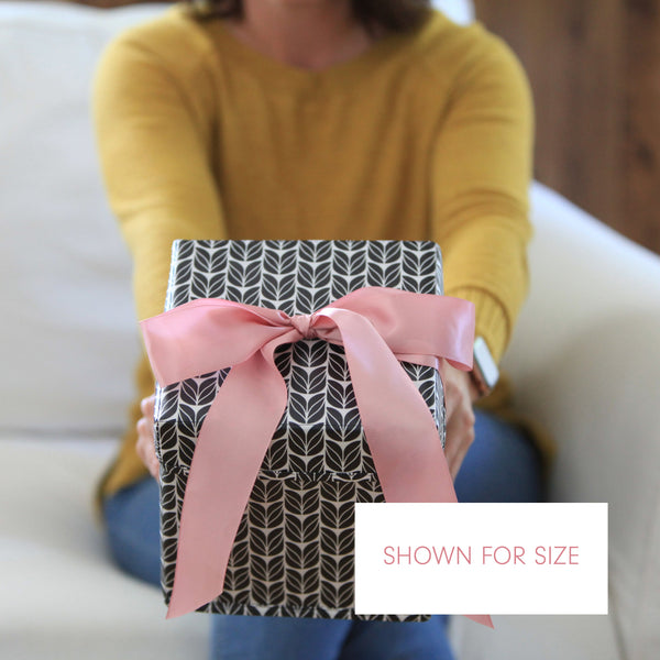 Person holding a gift box with a pink ribbon, shown for size.