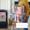 Person holding a stack of gift boxes with ribbons in a home setting