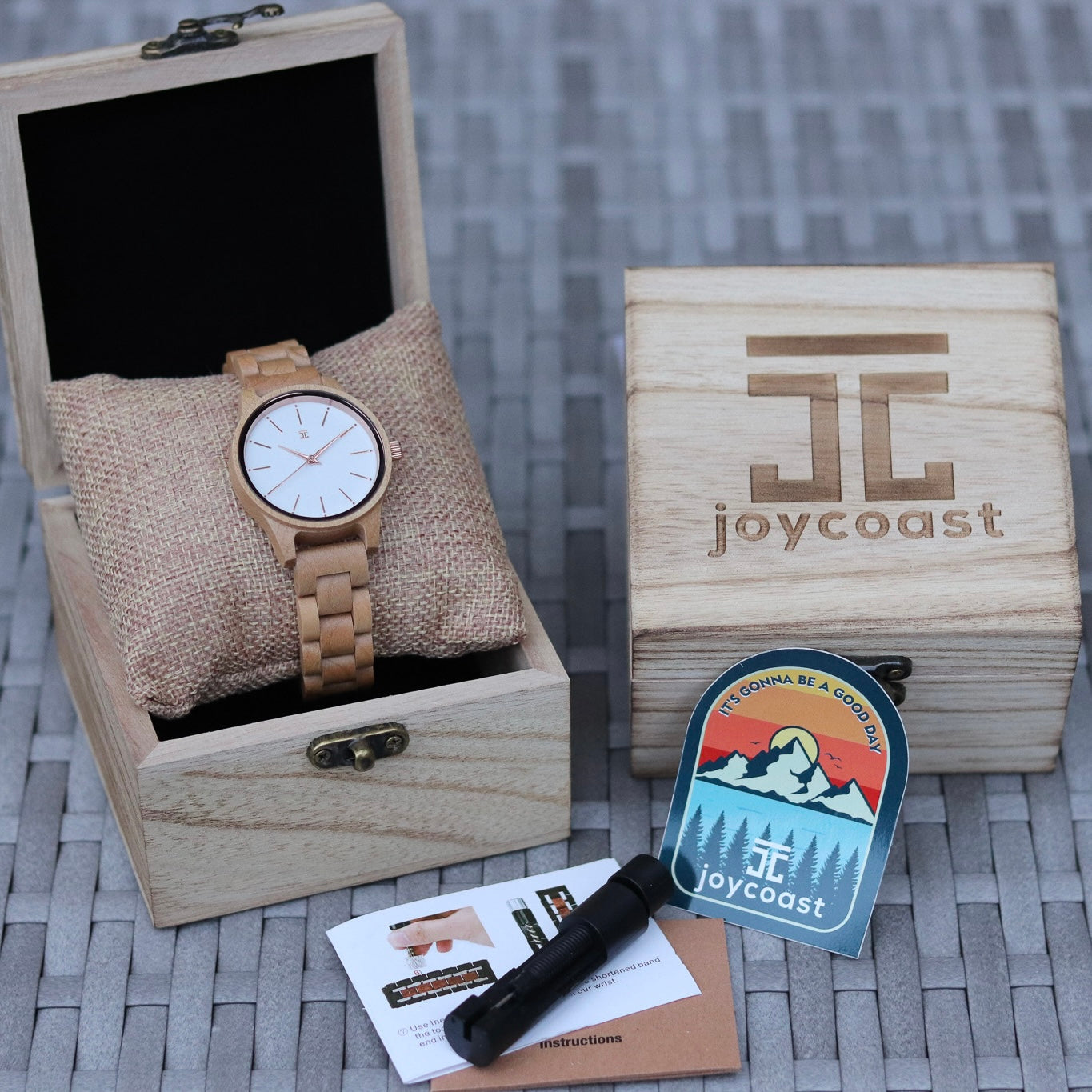 Wooden watch in a box with 'joycoast' branding on a textured surface