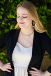 Close-up of Fair Anita hammered crescent loop earrings showing black and brass texture detail