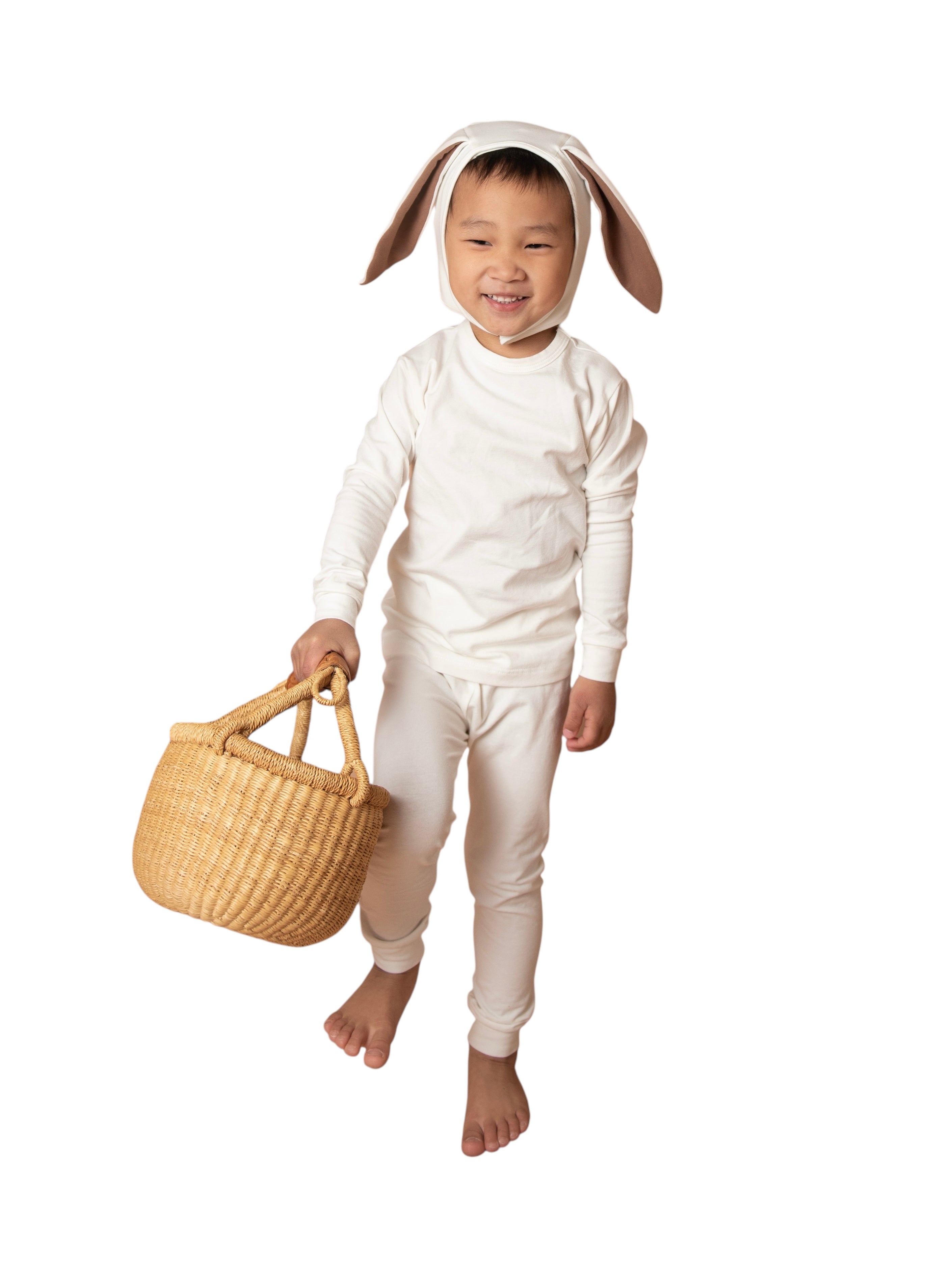 Child wearing a bunny costume holding a woven basket on a white background