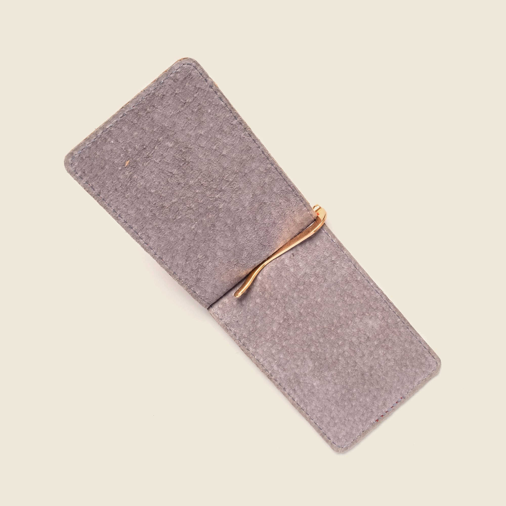 Gray phone case with a gold clip on a beige background