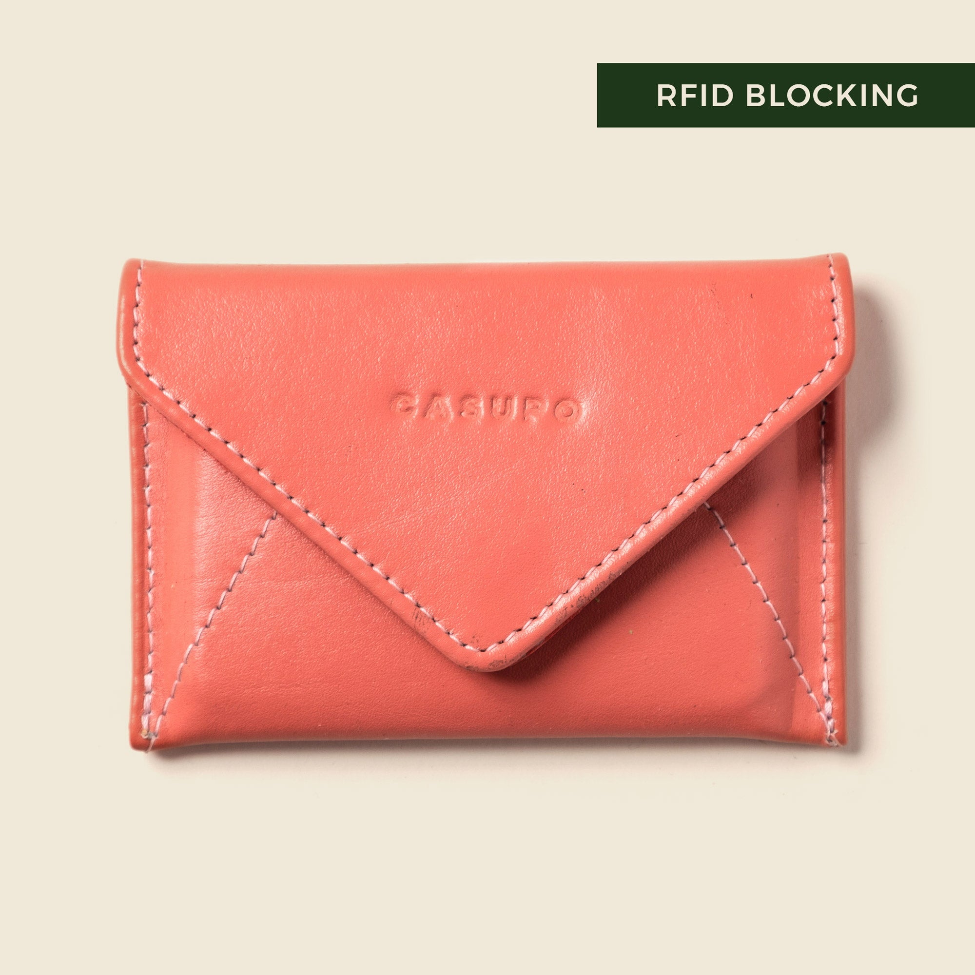 Pink leather wallet with 'Casu' branding on a beige background, featuring RFID blocking text.