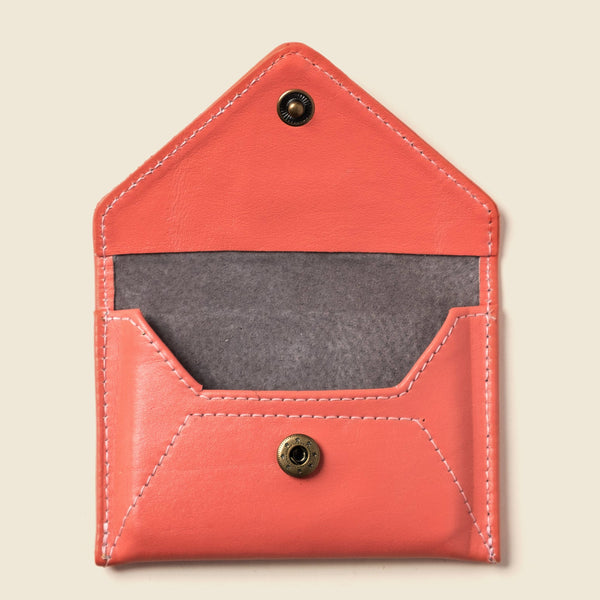 Red leather cardholder with gray interior on a beige background