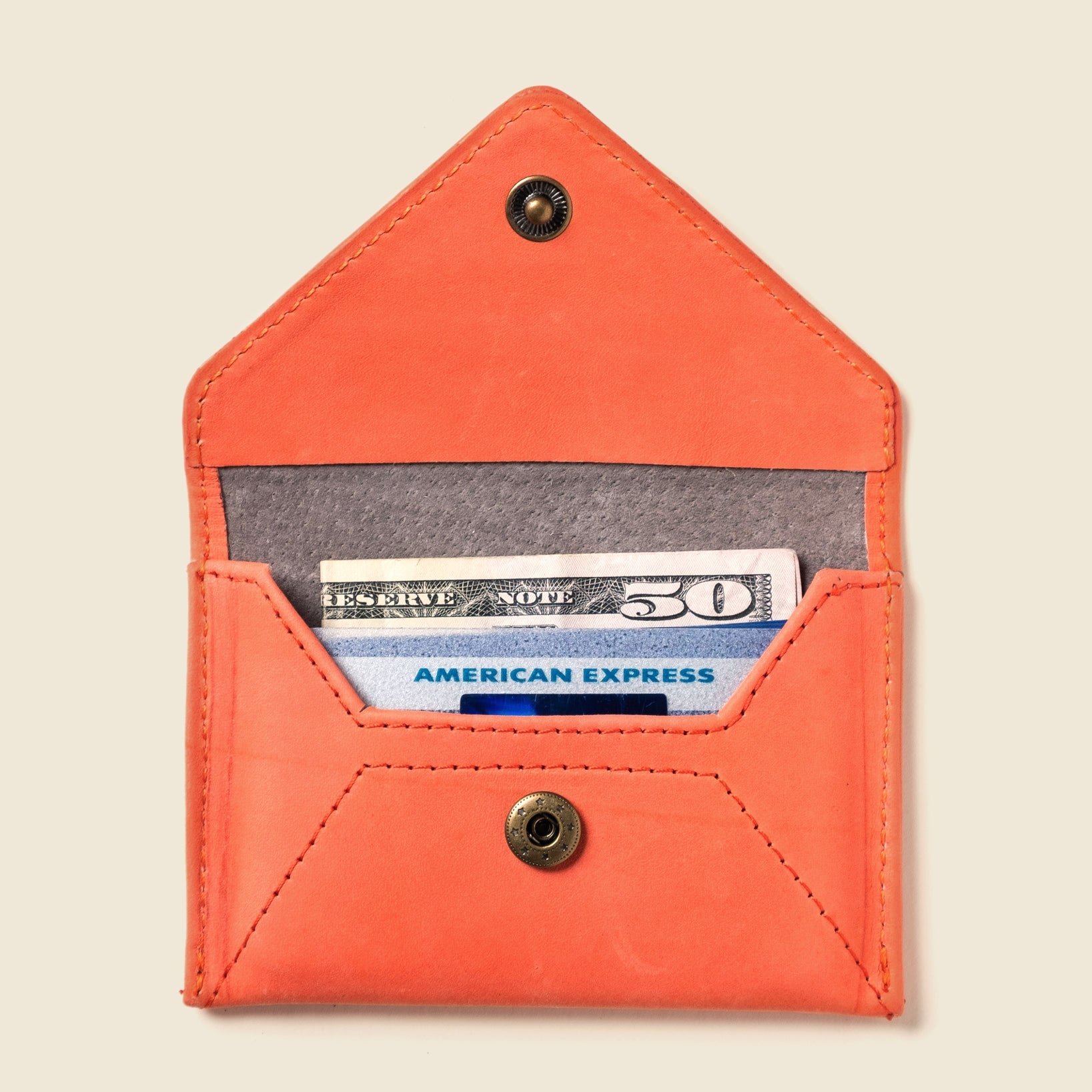 Orange leather wallet with American Express card and cash on a beige background