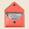 Coral leather wallet with American Express card and cash on a beige background