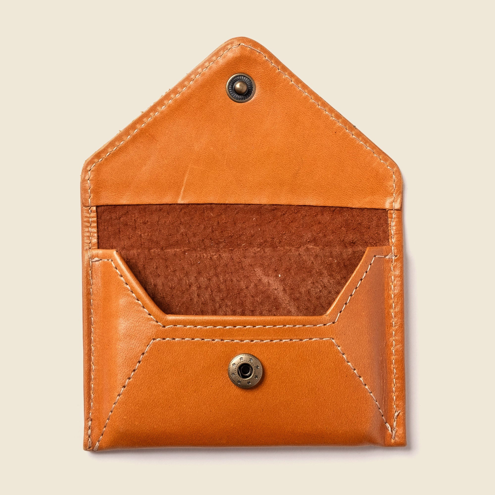 Brown leather pouch with button closures on a beige background