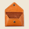 Brown leather pouch with button closures on a beige background