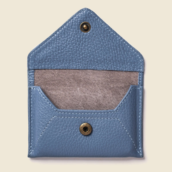 Blue leather cardholder with brass buttons on a beige background