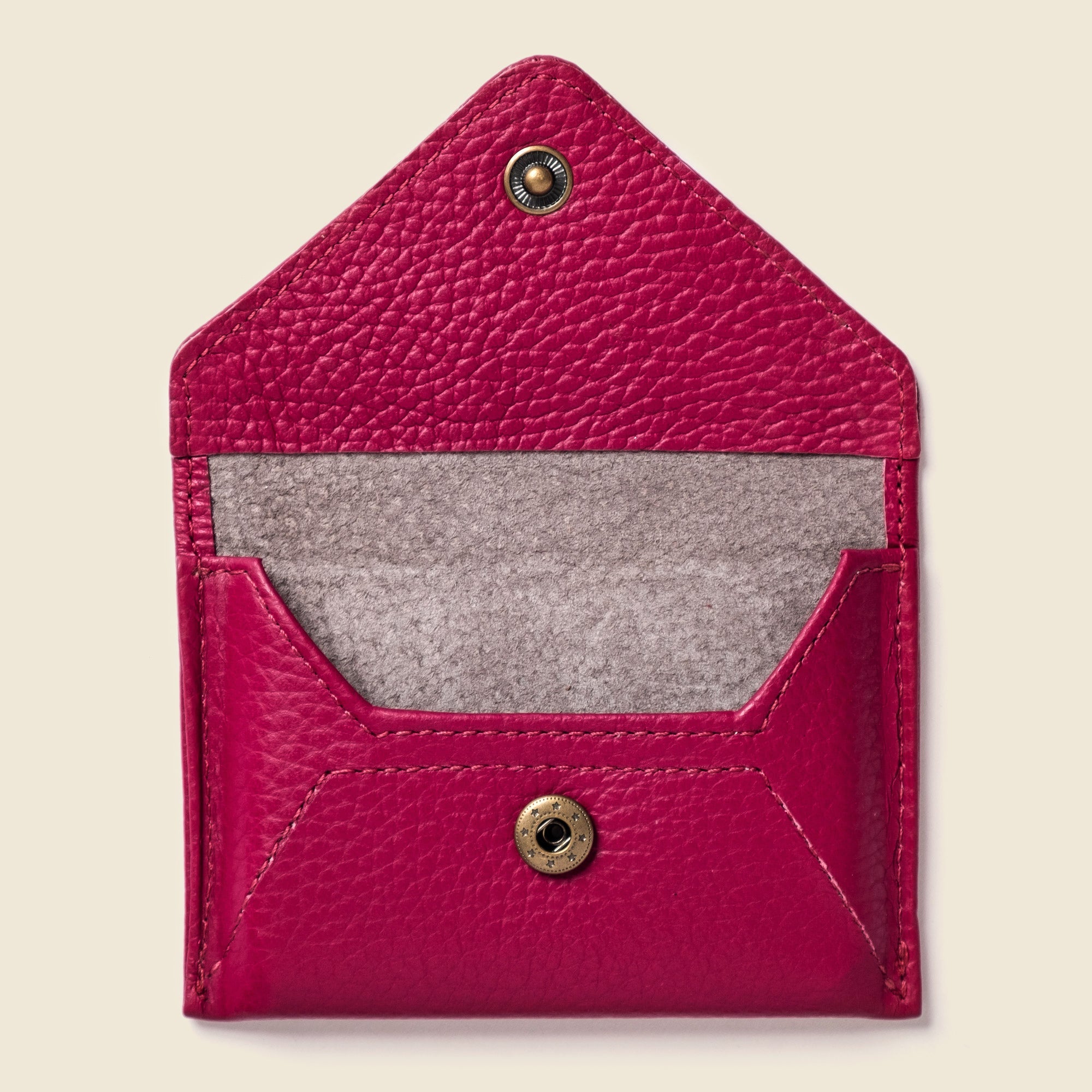Pink leather cardholder with gray interior on a beige background