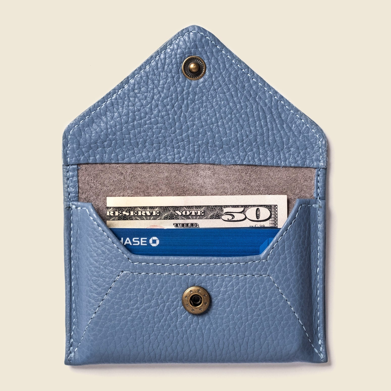 Blue leather wallet with a $30 bill and card inside on a beige background