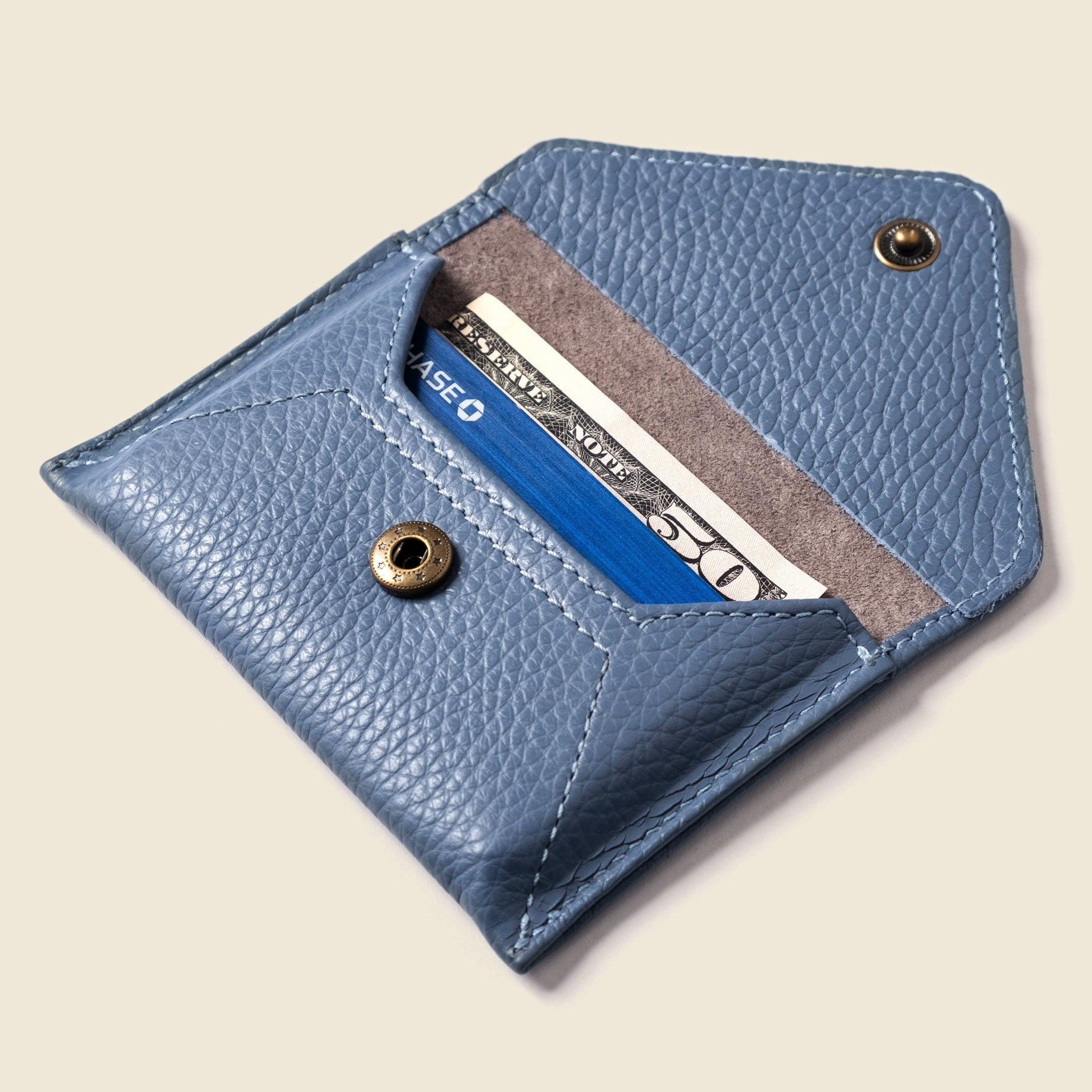 Blue leather cardholder with a card inside on a beige background