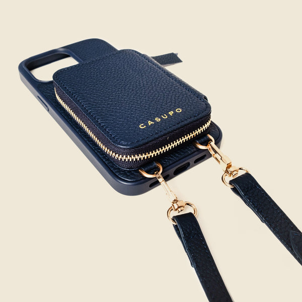 Navy blue phone case with gold zipper and matching strap on a beige background