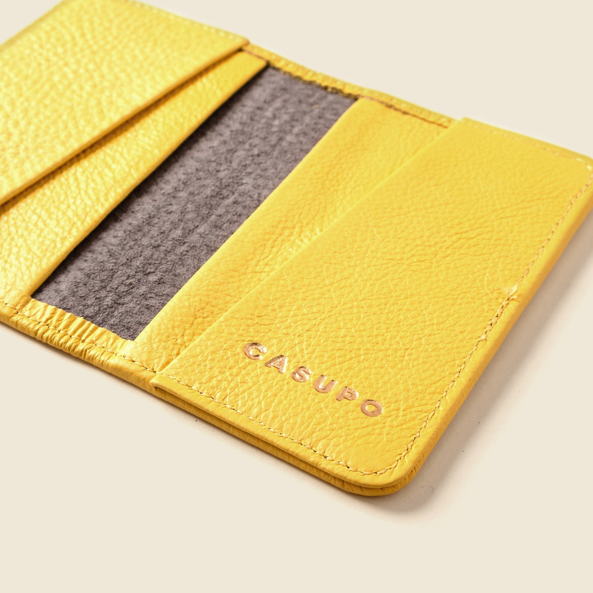 Yellow leather cardholder with 'Casupo' branding on a light beige background