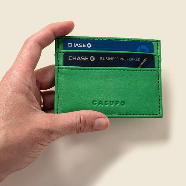 Green cardholder with Chase cards inside, held by a hand against a beige background