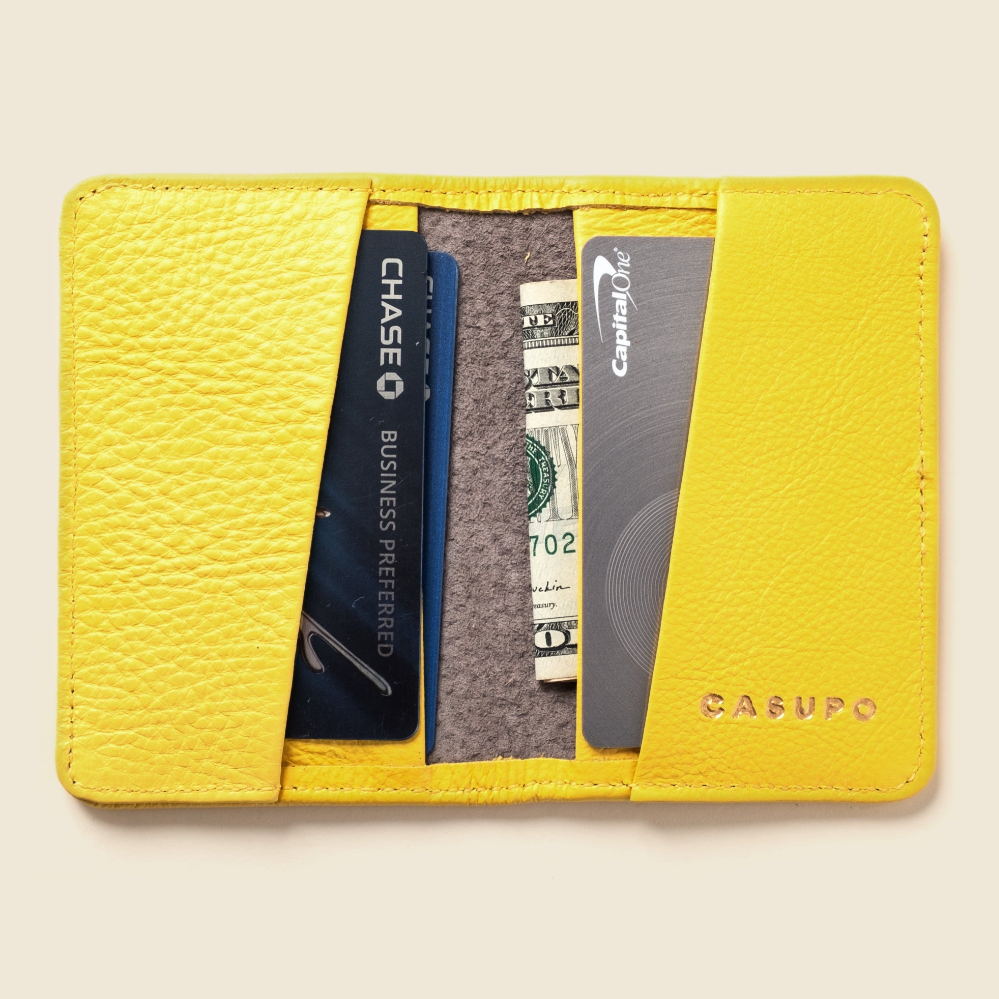 Yellow cardholder with cards and money on a beige background