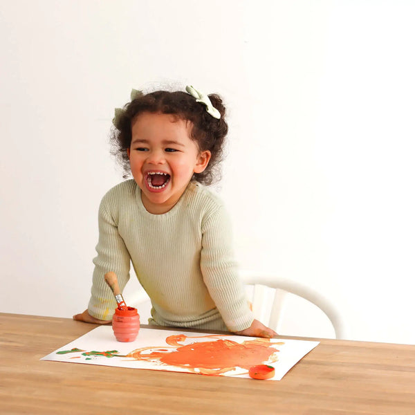 Child's painted hands covered in colourful Honeysticks washable finger paint