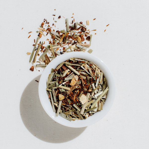 Loose leaf French Lemon Ginger organic herbal tea blend with dried ginger, lemongrass, and lemon verbena in a white bowl on a light gray background